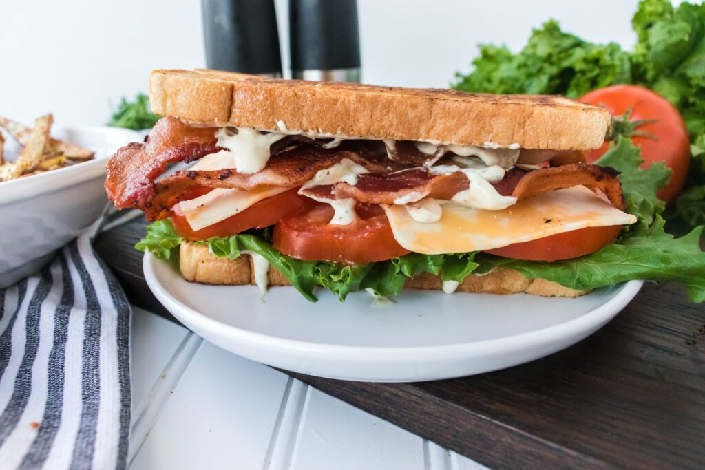 blt sandwich on a plate drizzled in sauce