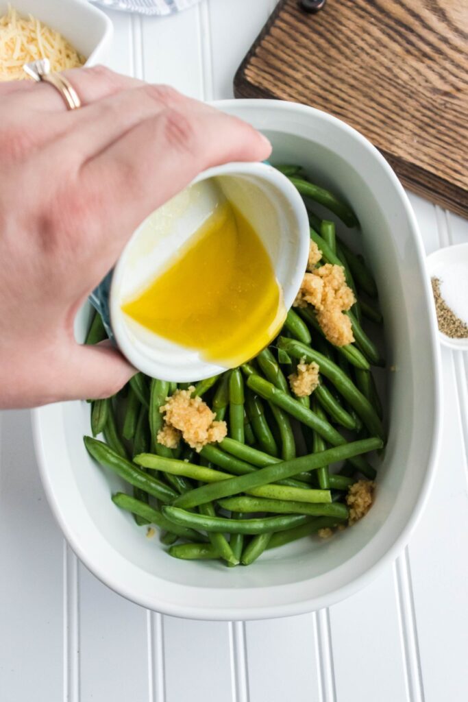 fresh green beans with melted butter being poured on them