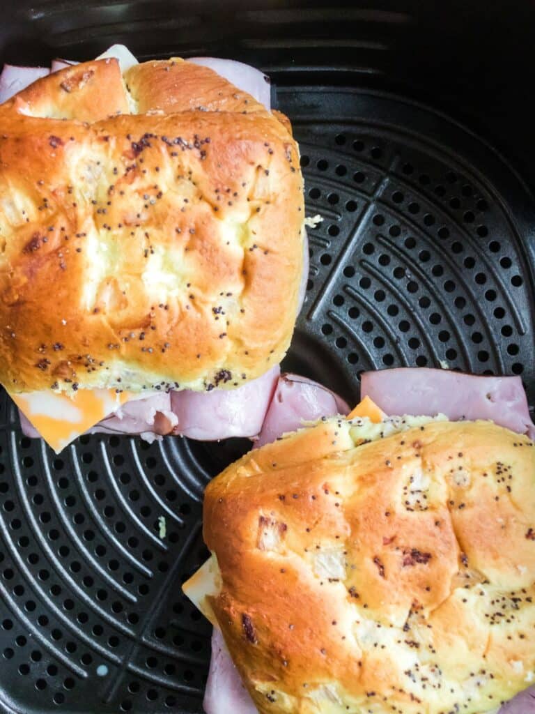 two ham and cheese sandwiches in air fryer basket