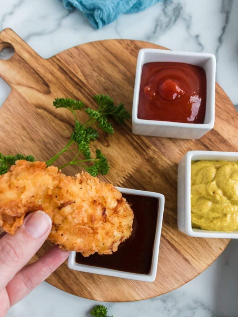 dipping chicken tender into barbecue sauce