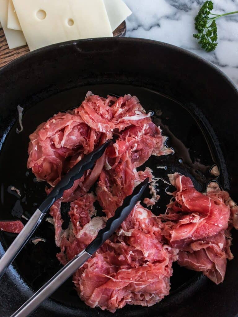 browning shredded beef in a cast iron skillet