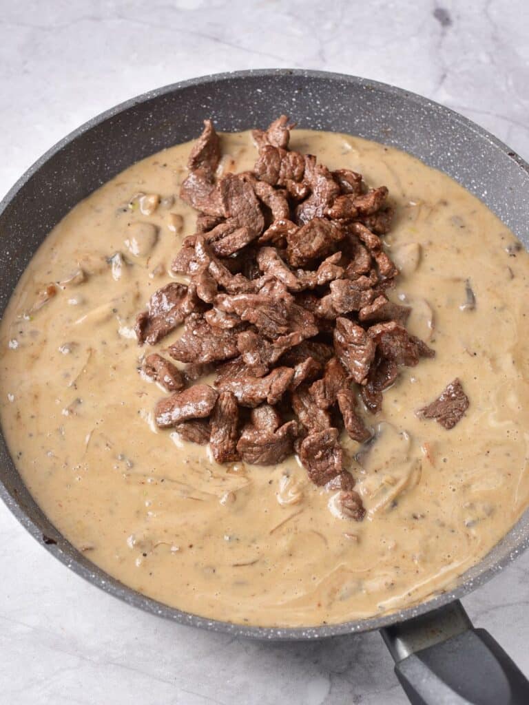 mixing steak into stroganoff sauce